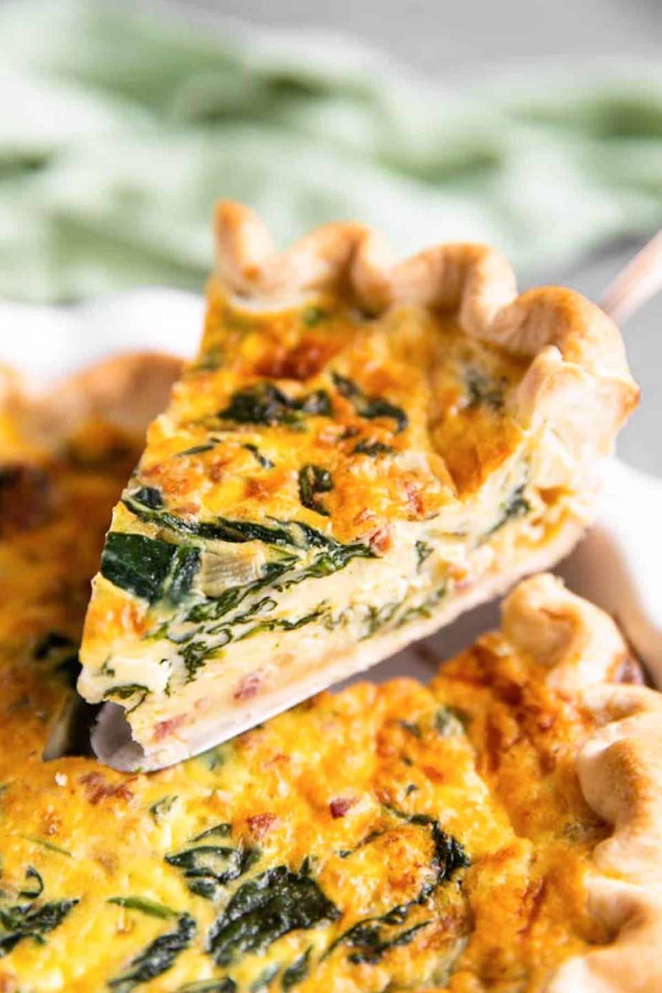 A perfect slice of quiche, ready to be eaten.